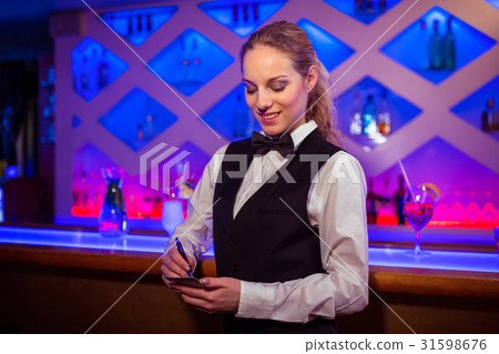 Young barmaid writing in notepad 31598676
