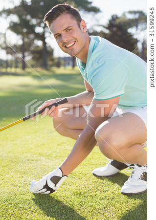 Portrait of confident golfer man placing golf ball on tee Portrait of confident golfer man placing golf ball on tee 31599248