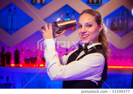 Barmaid with cocktail shaker at counter 31599377