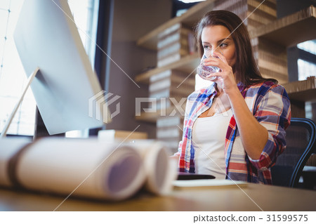Businesswoman looking at computer while drinking water 31599575