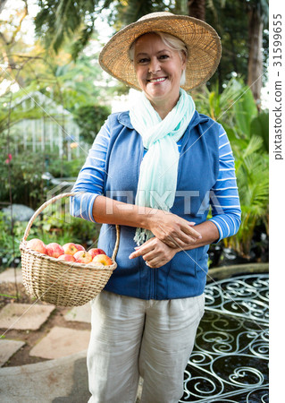 Portrait of happy woman standing with apples at garden Portrait of happy woman standing with apples at garden 31599655