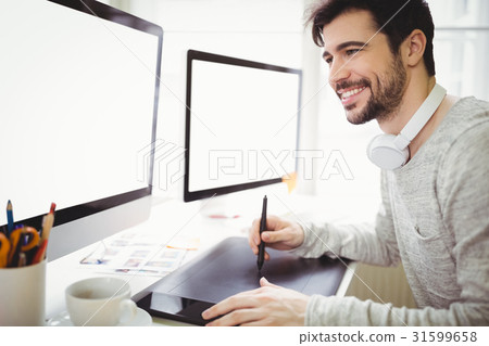 Businessman using graphics tablet in front of computers 31599658