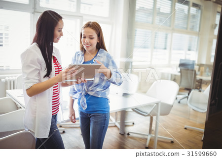 Female colleagues discussing with digital tablet in creative office Female colleagues discussing with digital tablet in creative office 31599660