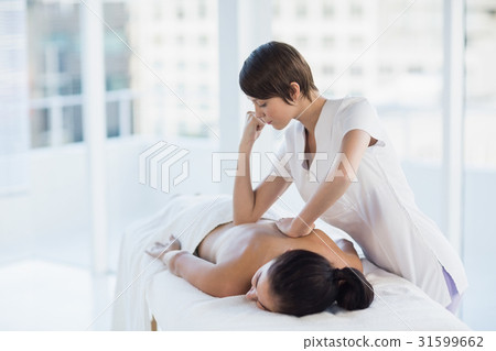 Masseuse giving massage to naked woman Masseuse giving massage to naked woman 31599662