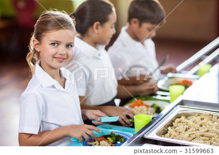 Schoolgirl with classmate standing near canteen counter Schoolgirl with classmate standing near canteen counter 31599663