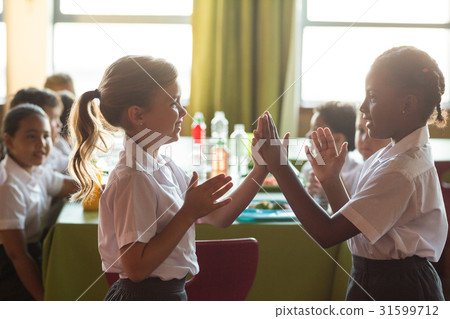 Smiling schoolgirls playing clapping game 31599712