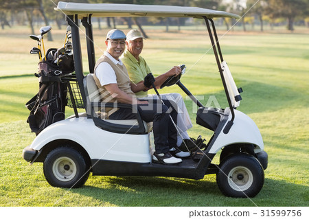 Happy male golfer friends sitting in golf buggy Happy male golfer friends sitting in golf buggy 31599756