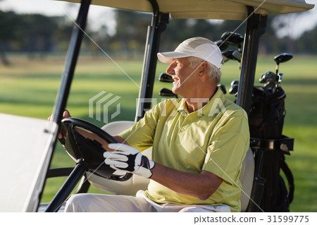 Smiling mature man driving golf buggy Smiling mature man driving golf buggy 31599775