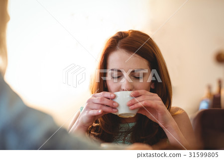 Beautiful woman sipping coffee with friend at cafe 31599805