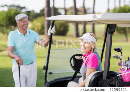 Smiling mature woman sitting in golf buggy 31599821