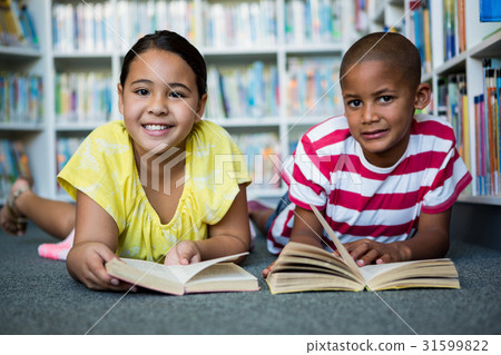 Portrait of students reading books while lying at library 31599822