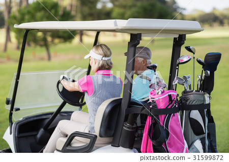 Mature woman driving golf buggy Mature woman driving golf buggy 31599872