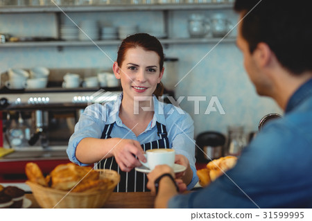 Portrait of confident barista giving coffee to customer at cafe 31599995