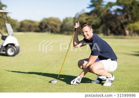 Side view of man placing golf ball on tee 31599996
