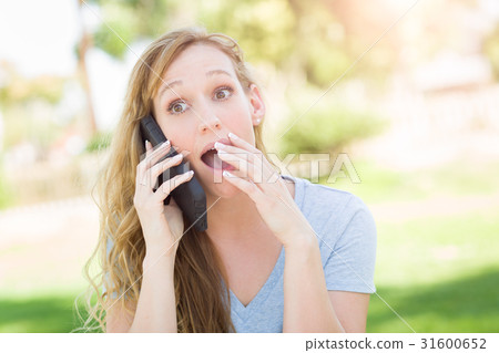 Stunned Young Woman Outdoors Talking on Her Smart Phone. 31600652