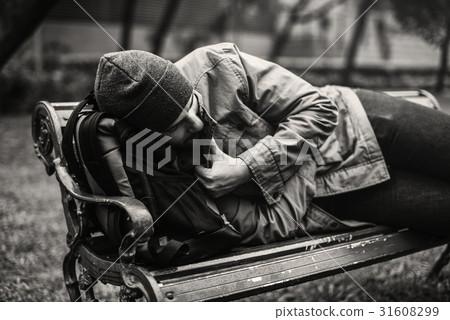 Homeless Adult Man Sleeping on Bench in The Park Homeless Adult Man Sleeping on Bench in The Park 31608299