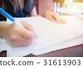 women sitting at desk and writing on notebook 31613903