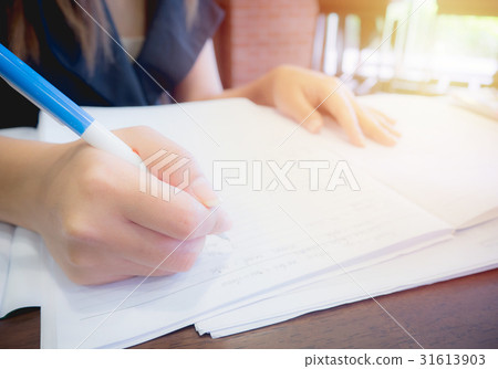 women sitting at desk and writing on notebook women sitting at desk and writing on notebook 31613903
