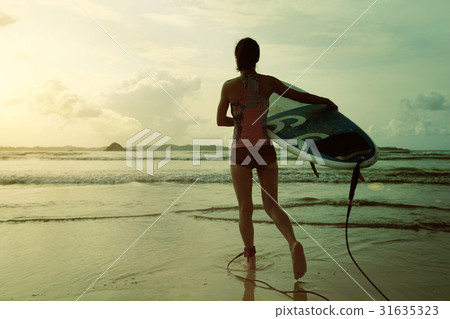 young woman surfer ready to surf on a beach young woman surfer ready to surf on a beach 31635323