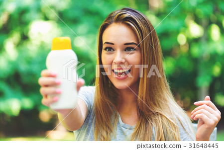 Young woman a bottle of sunblock outside Young woman a bottle of sunblock outside 31648445