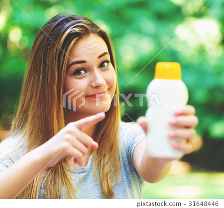 Young woman a bottle of sunblock outside Young woman a bottle of sunblock outside 31648446