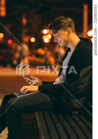 Young man with laptop in night city Young man with laptop in night city 31660593