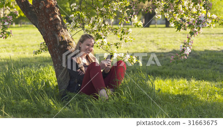 teenage girl sitting under blossoming pink apple teenage girl sitting under blossoming pink apple 31663675