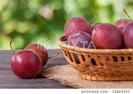 plum in a wicker basket on the wooden table with 31664545