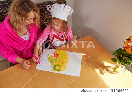 A mom and girl preparing cookies A mom and girl preparing cookies 31664793