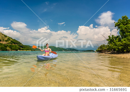 Young woman paddling during vacation in an idyllic Young woman paddling during vacation in an idyllic 31665691
