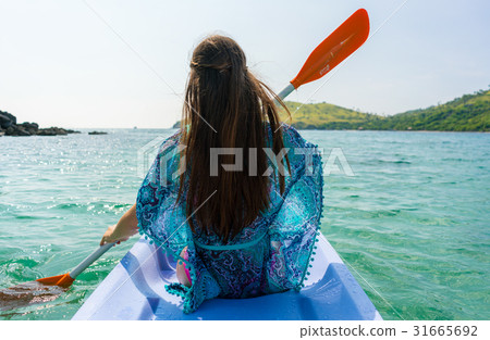 Young woman paddling a canoe along the shore of an 31665692