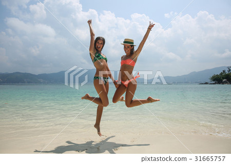 Two cool trendy hipster girls jumping on the beach Two cool trendy hipster girls jumping on the beach 31665757