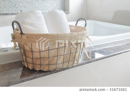 Towels in basket next to white bathtub in bathroom Towels in basket next to white bathtub in bathroom 31671081