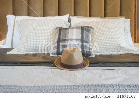 Brown hat on center of bed with pillows Brown hat on center of bed with pillows 31671105