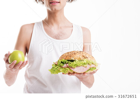 Thin guy choosing between fruit and sandwich 31672651