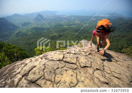 young woman climber climbing rock at mountain top 31673958