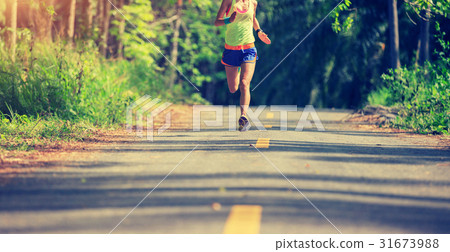 Young woman running at tropical forest trail 31673988