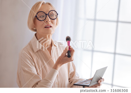 Modern grandmother using powder rouge 31686308