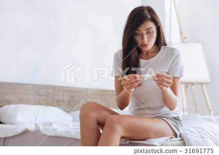 Surprised young lady looking at pregnancy test 31691775