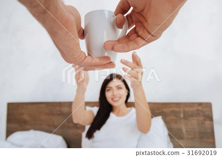 Male hands giving cup of coffee to brunette 31692019