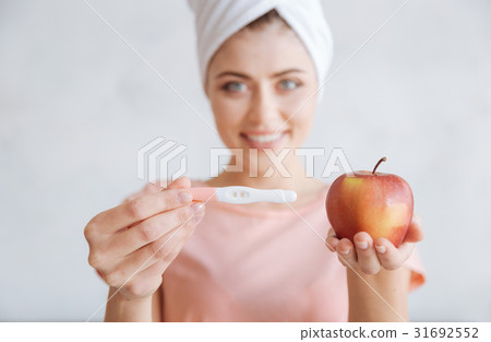 Portrait of woman holding pregnancy test and apple 31692552