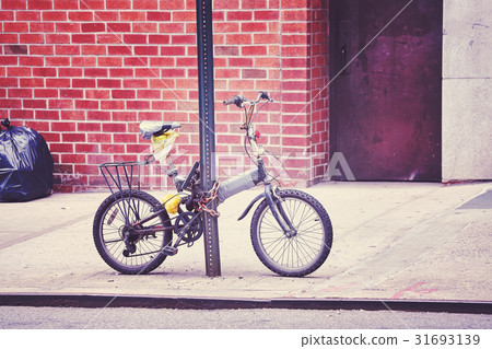 An old bicycle locked to a sign post in Chinatown. 31693139