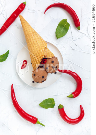 Chocolate ice cream with chilli in a waffle cone. 31694660