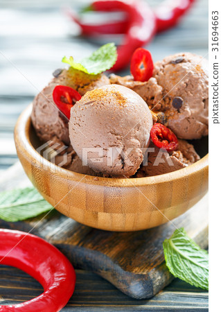 Bowl with chocolate ice cream and chili pepper. 31694663