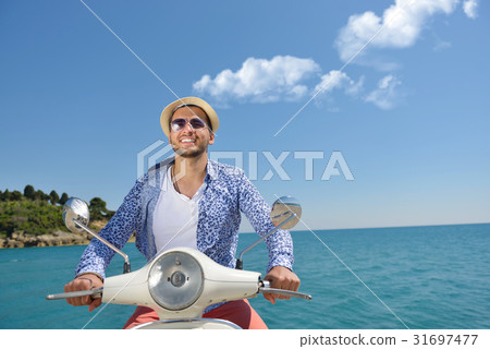 Handsome man posing on a scooter in a vacation 31697477