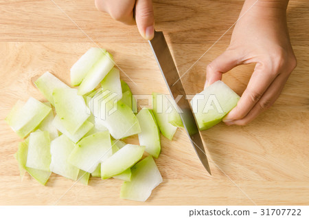 Woman cutting wax gourd on wooden board,cooking Woman cutting wax gourd on wooden board,cooking 31707722