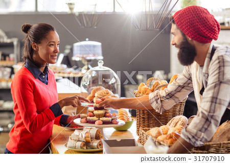 Seller serving a cake to the customer Seller serving a cake to the customer 31707910