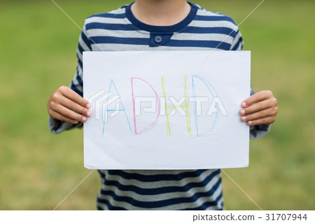 Boy in park holding placard that reads alphabets Boy in park holding placard that reads alphabets 31707944