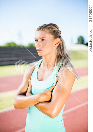 Female athlete standing with arms crossed on the running track Female athlete standing with arms crossed on the running track 31708094