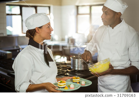 Chefs talking to each other while working in kitchen 31709163